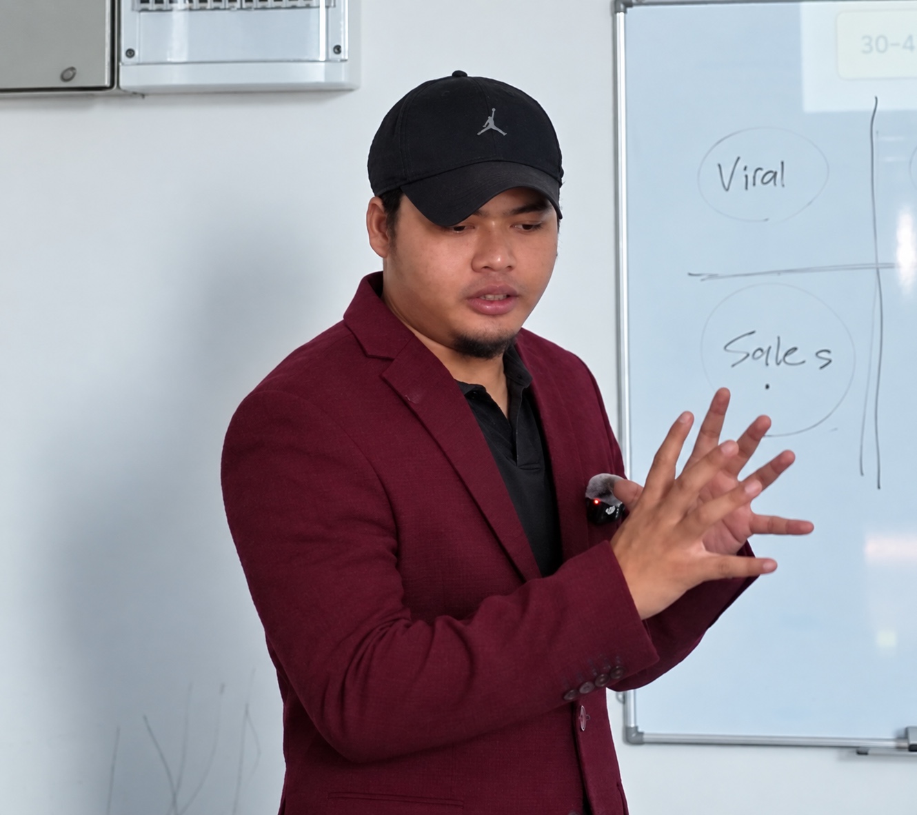 Coach Am mengajar sambil menerangkan idea di papan putih, dalam sesi coaching
