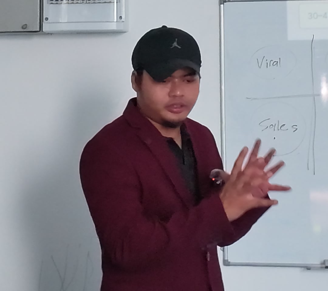 Coach Am mengajar sambil menerangkan idea di papan putih, frame asal daripada rakaman DJI