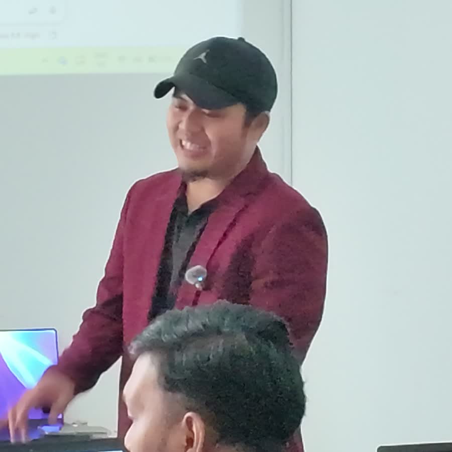 Coach Am berbincang dengan peserta di meja laptop semasa sesi coaching Oktober 2026
